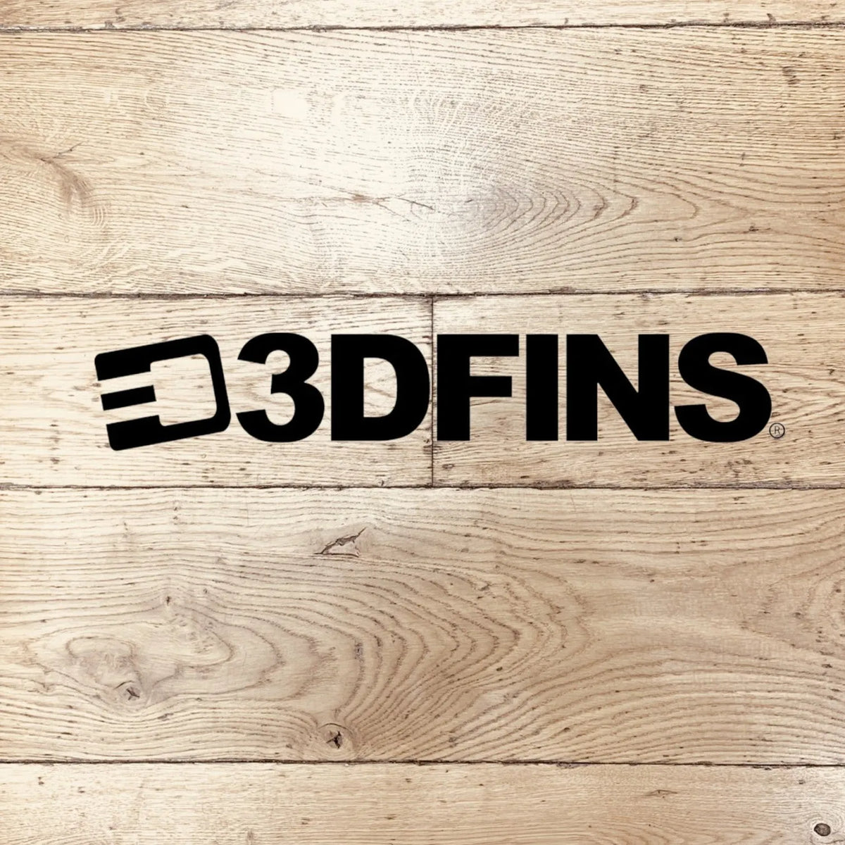 3DFINS logo in black on light natural wood plank surface with prominent wood grain texture