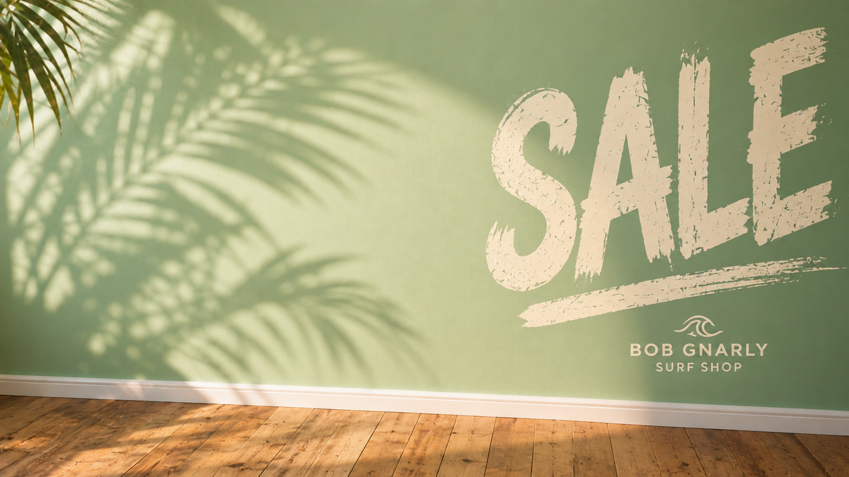 Surfer riding a large turquoise wave at sunrise, text overlay Bob's Gnarly Sale