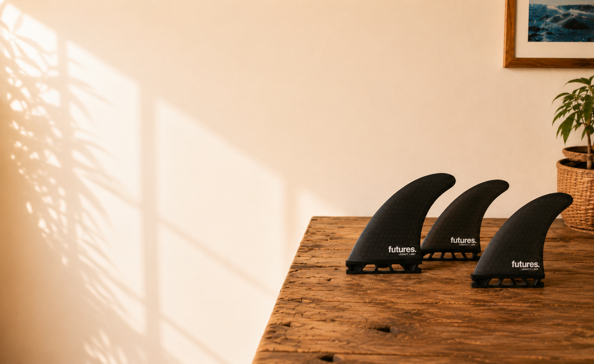 Close-up of three black surfboard thruster fins on wooden table with Bob Gnarly Surf logo