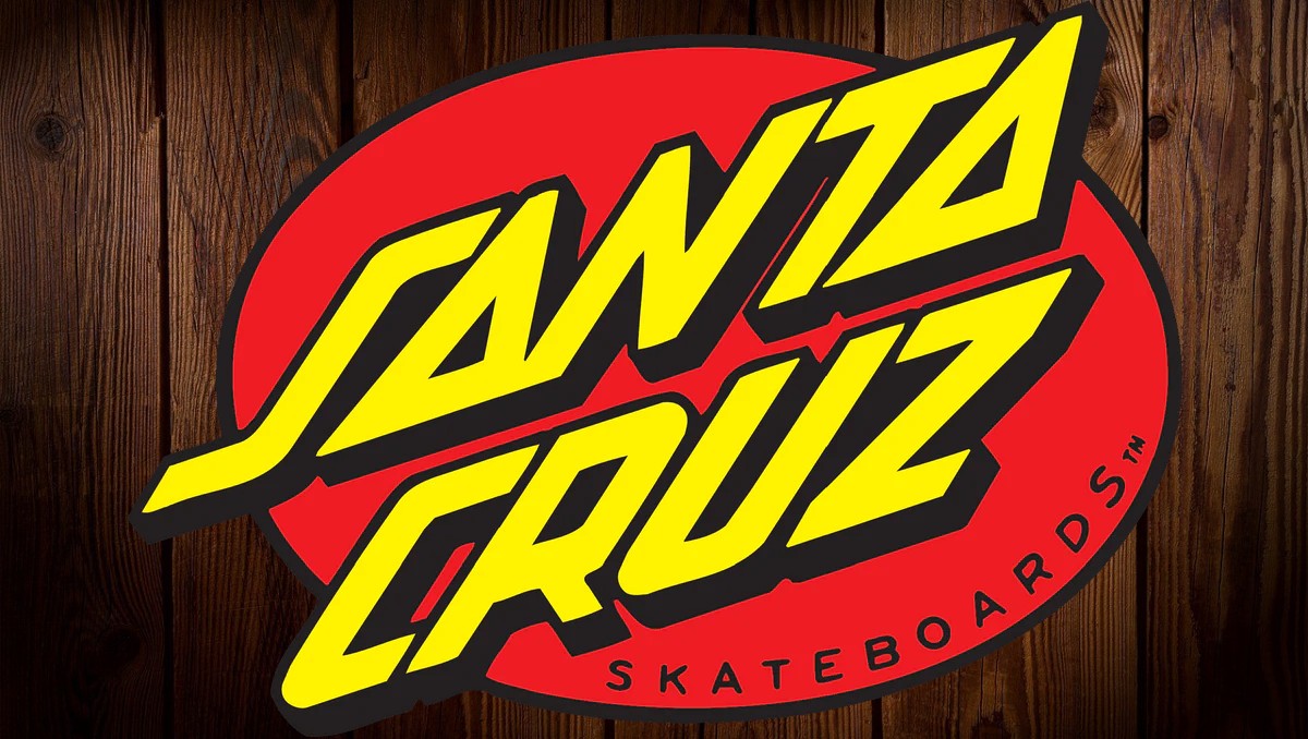 Santa Cruz Skateboards logo with bold yellow text on red oval background, wooden wall backdrop