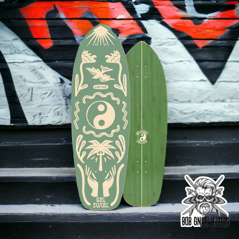 Two green Carver surf skateboards with yin yang design and palm tree graphics against graffiti wall